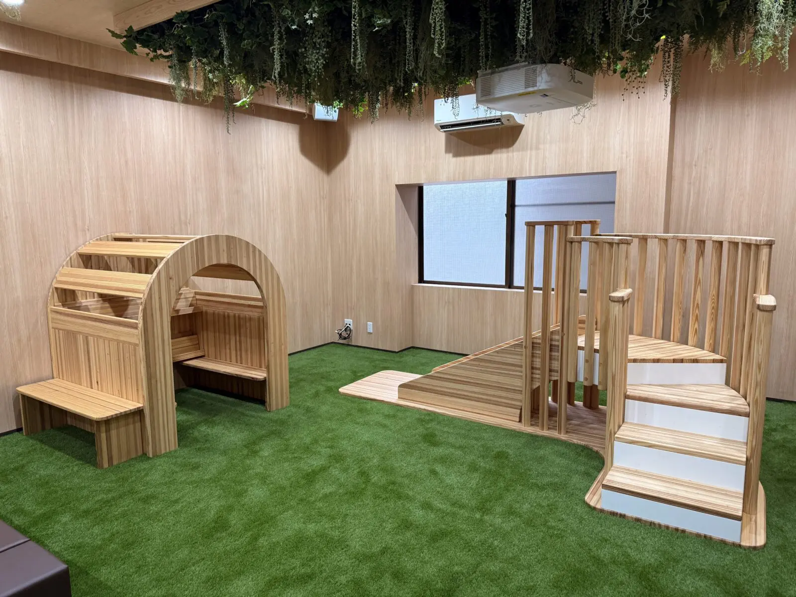 木製遊具と絵本家具を配置したキッズスペース