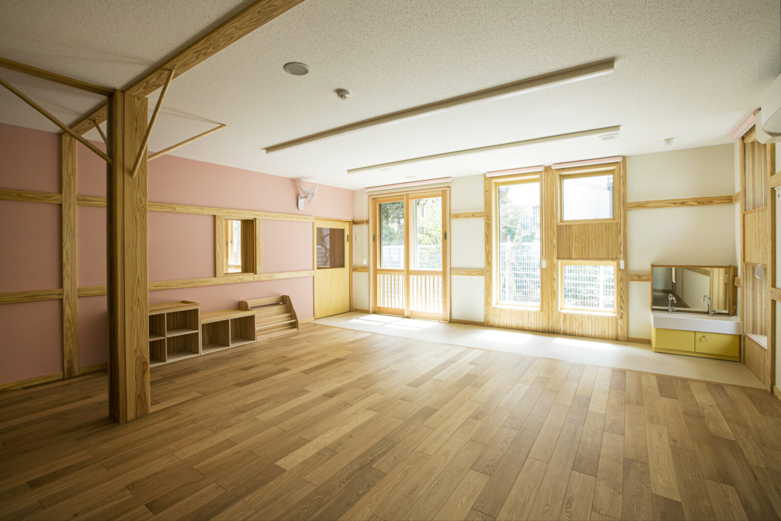 ピンクの壁と木製家具がある保育室