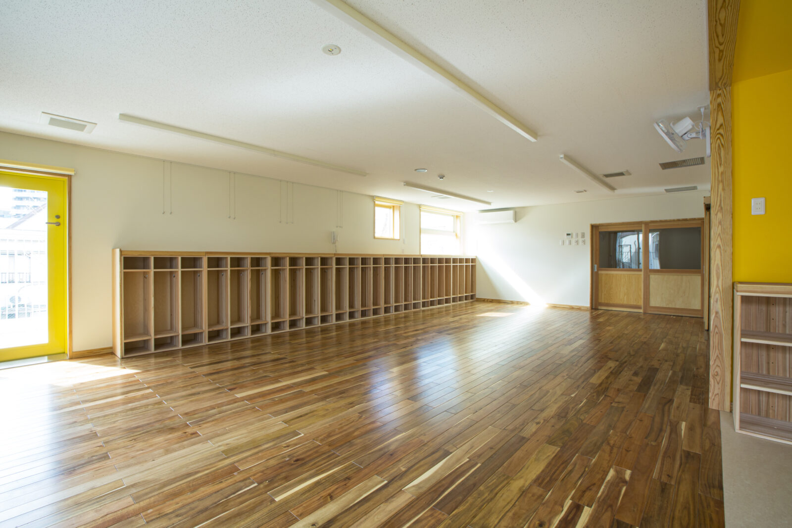 木製ロッカーが並ぶ広い保育室の全景